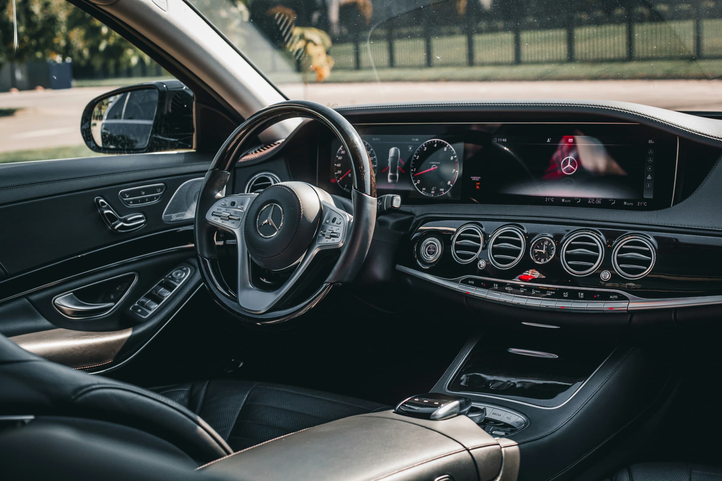 The chauffeur's view inside a polished executive sedan, dashboard and steering wheel detail